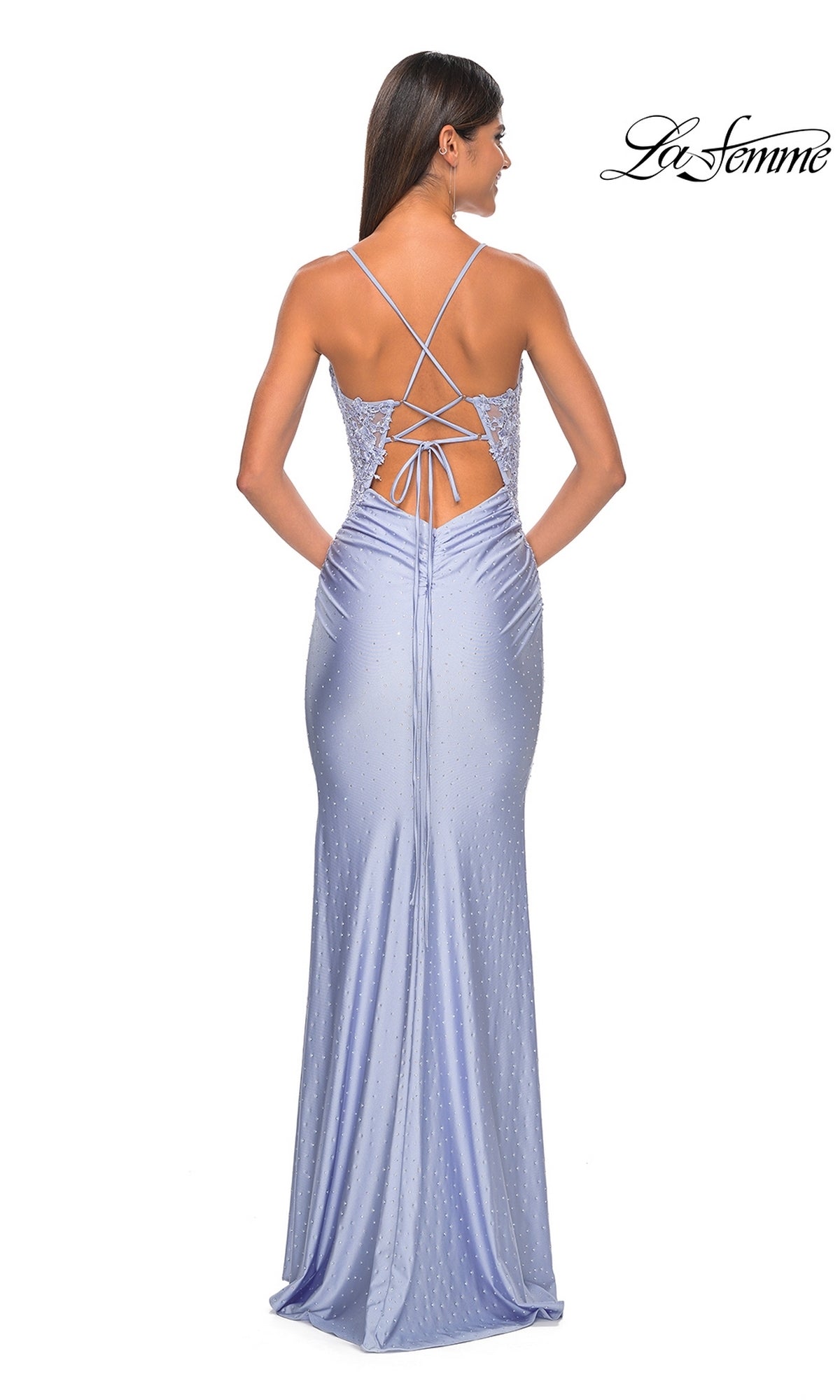 Woman in a light purple Lace-Side La Femme Long Beaded Prom Dress 31301 with a lace-up open back and thin crisscross straps, standing facing away.